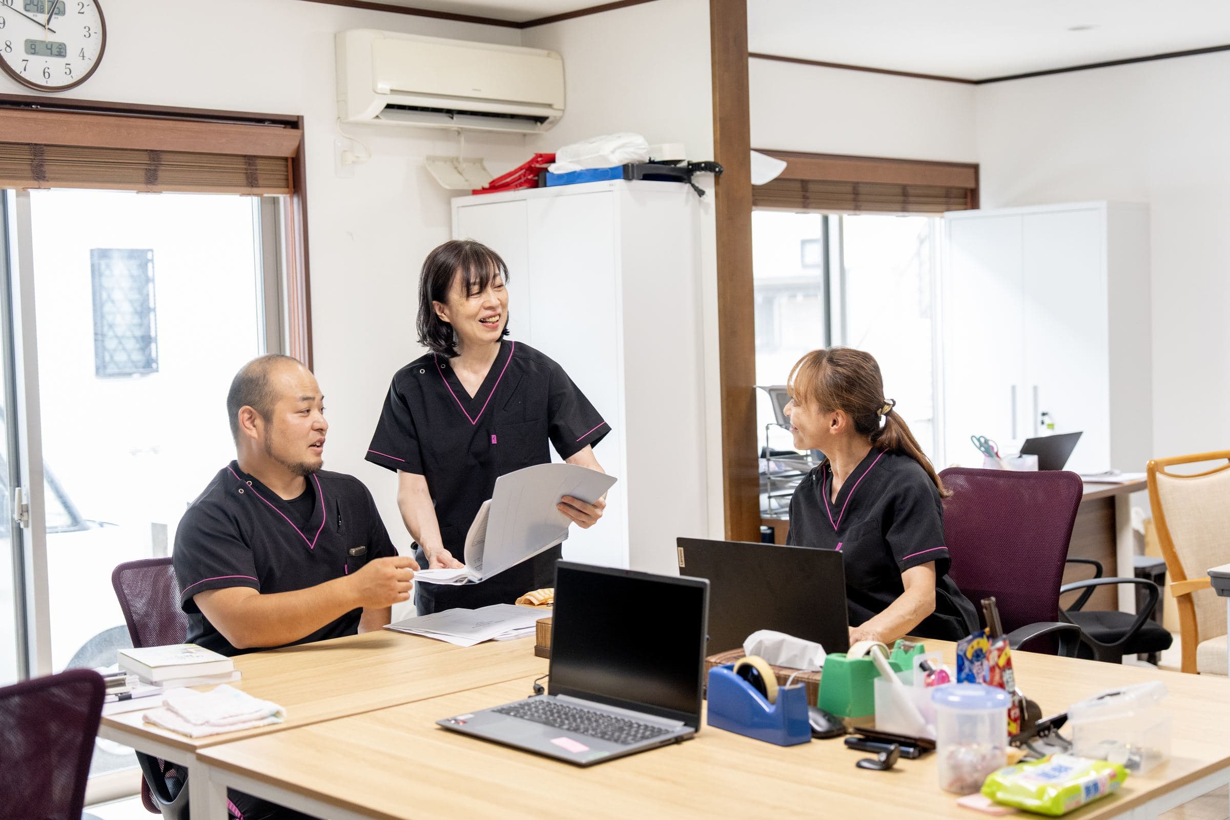 事務所で記録を見ながら話すスタッフ3名