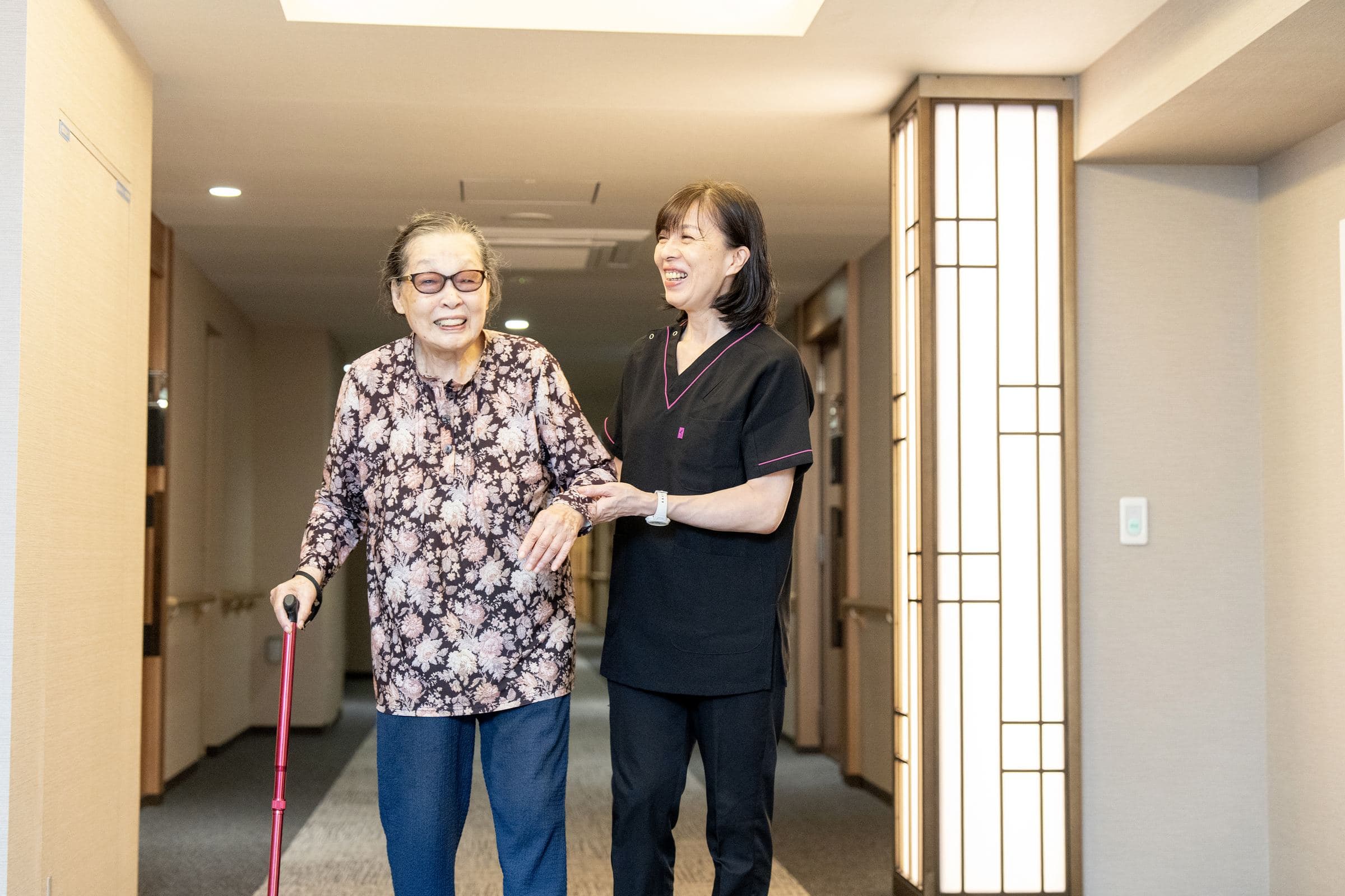 杖を使うご利用者に付き添って歩く看護師